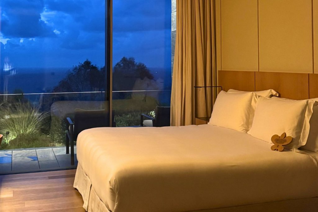 Akelarre guest room with ocean-view balcony and Relais & Châteaux wooden flower symbolizing sustainable linen practices