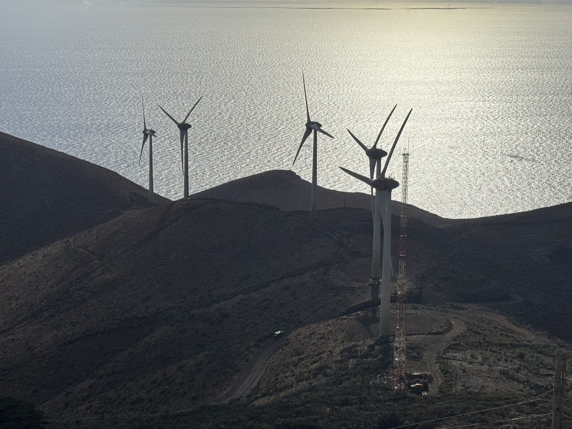 Wind turbines of the Gorona del Viento plant on a dark volcanic ridge above the Atlantic, El Hierro