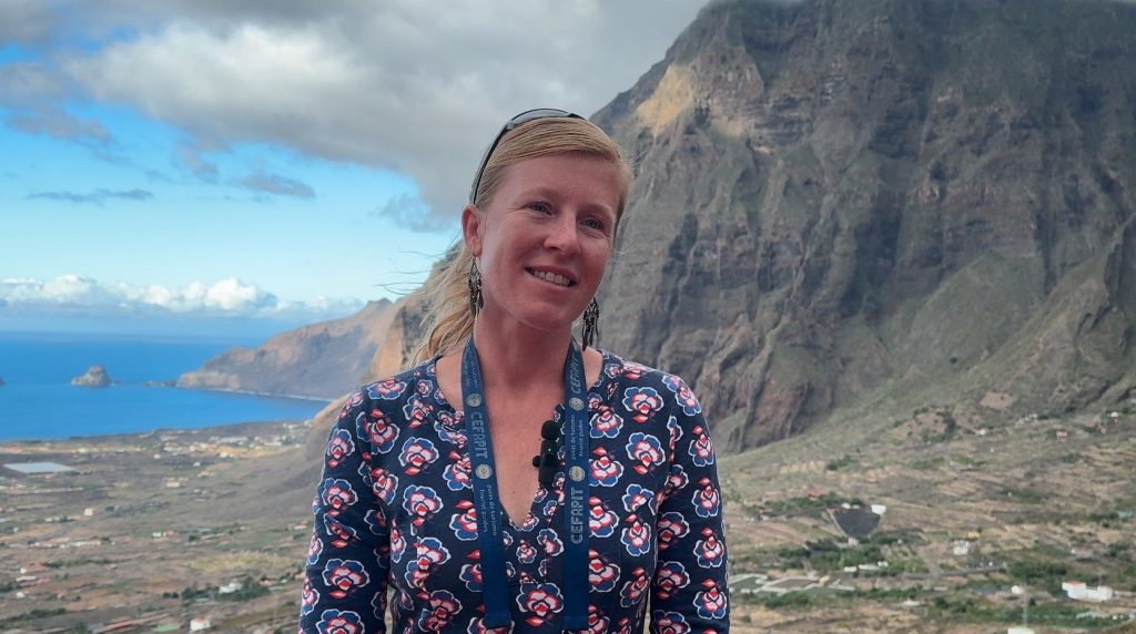Joanna Rudnik, a tour guide, smiling in front of the cliffs and plain of the El Golfo valley, El Hierro