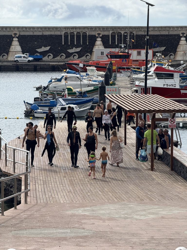 Divers in wetsuits walking along the dock of La Restinga harbour, El Hierro